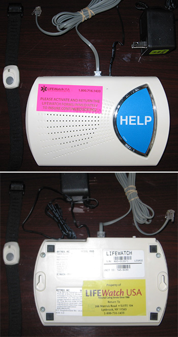 Life Watch alert device, top and bottom views, with accompanying power adapter, telephone cable, and wristband. Top of device has a large blue button labeled help and a pink LifeWatchUSA activation instruction label. Bottom has a yellow label 'Property of LifeWatchUSA' with address in Lynbrook, New York